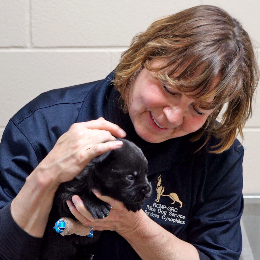Louise holding a small black puppy.